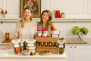 Two women in a kitchen with NUUDA products displayed.