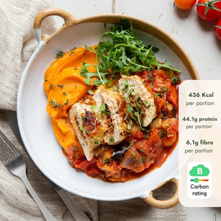 Dish with chicken, vegetables, and mashed sweet potato on a white plate with a fork and napkin.