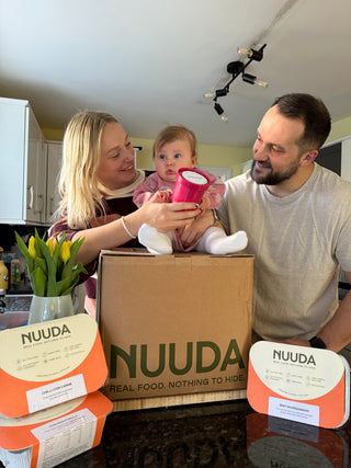 Family with a baby in a kitchen holding NUUDA products