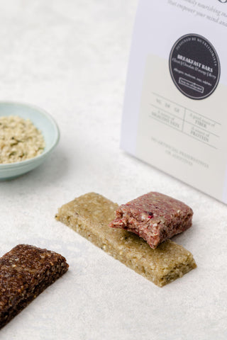 Two protein bars, one chocolate and one orange, with a pack in the background labeled 'prebiotic protein breakfast bars'.